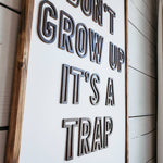 Don't grow up it's a trap wood sign