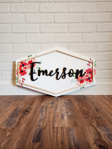 Floral Nursery Name Sign with soft red poppy florals in a watercolor style print with a raised border and name on a white backer. The shape is an elongated hexagon